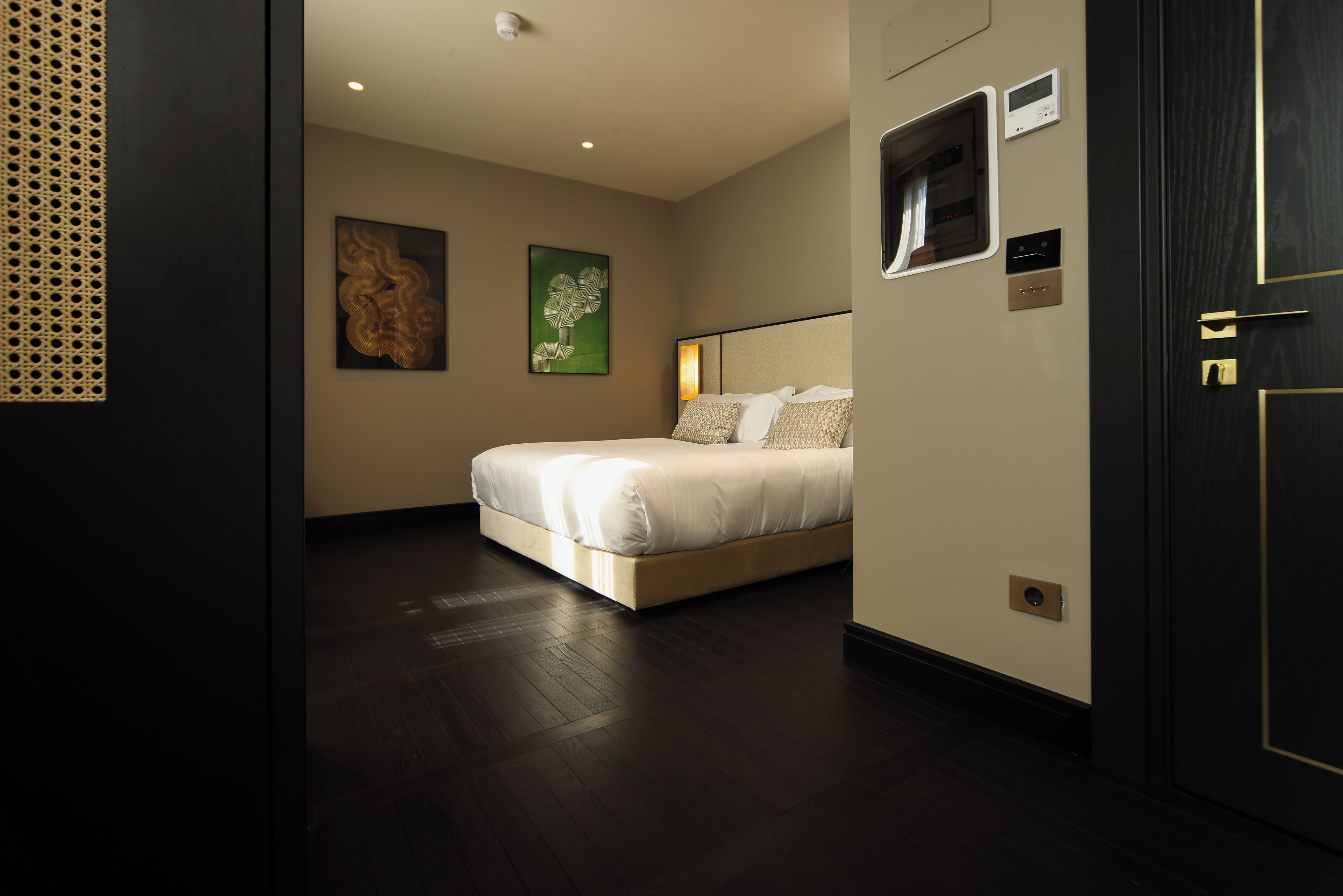 A modern hotel room with a large bed, a wall-mounted TV, and a door with a handle.