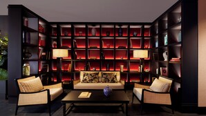 A modern living room with a sofa, two armchairs, a coffee table, and a bookshelf filled with decorative items. - U-Visionary Venezia Hotel (Venice)
