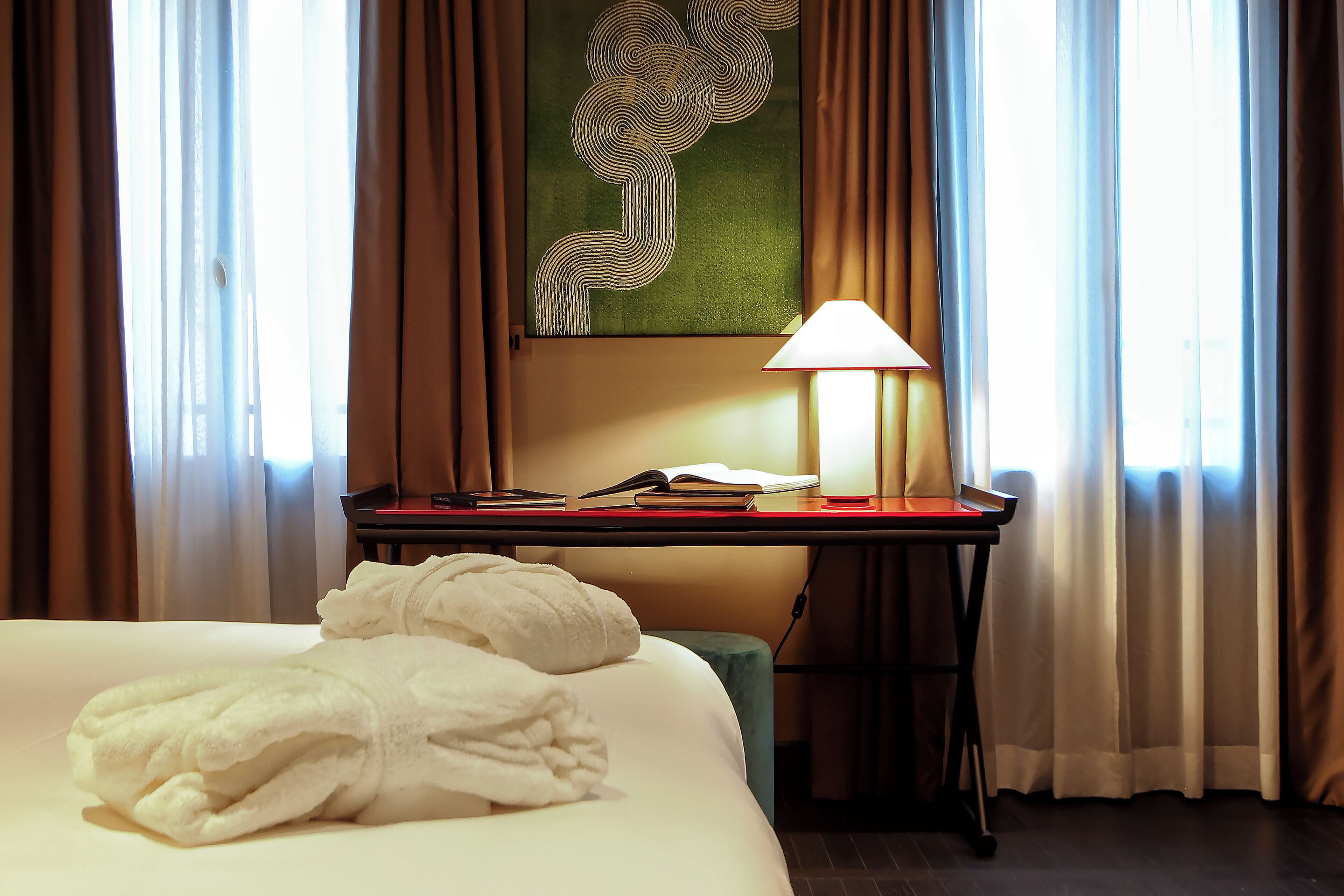 Ein Hotelzimmer mit Bett, Schreibtisch mit Lampe und einem Bild an der Wand.