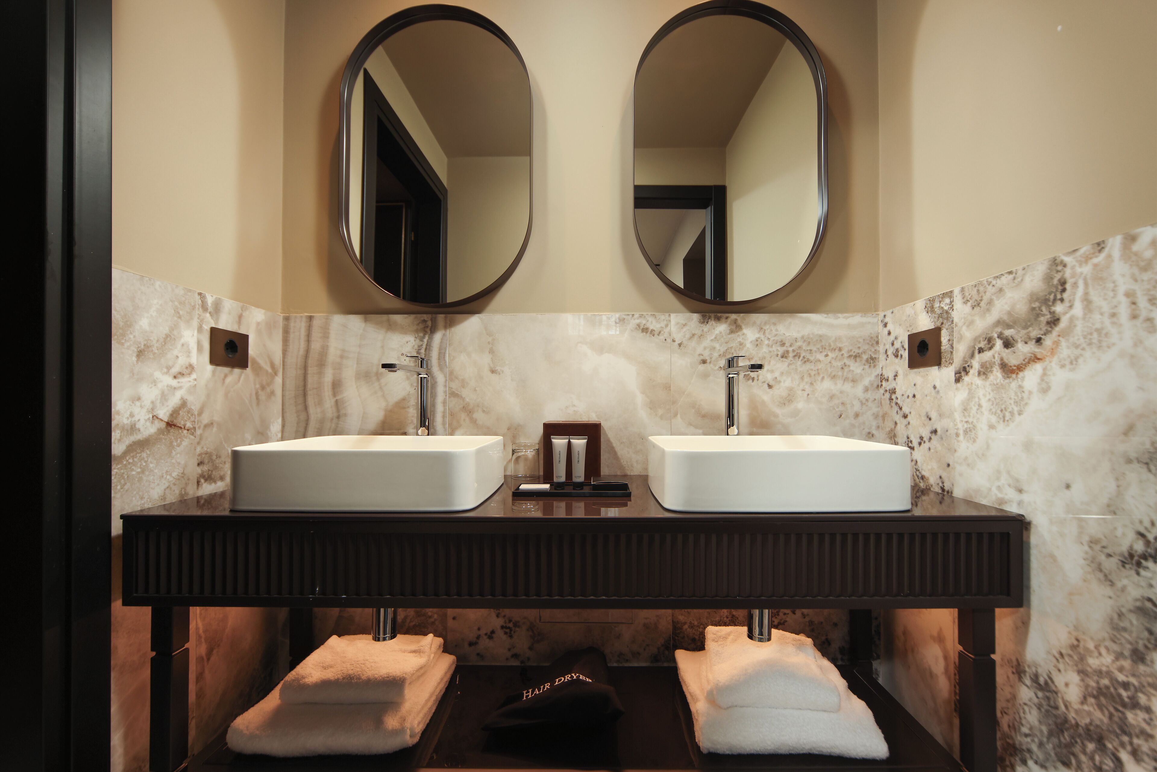 A bathroom with two sinks, a mirror, and a towel rack.
