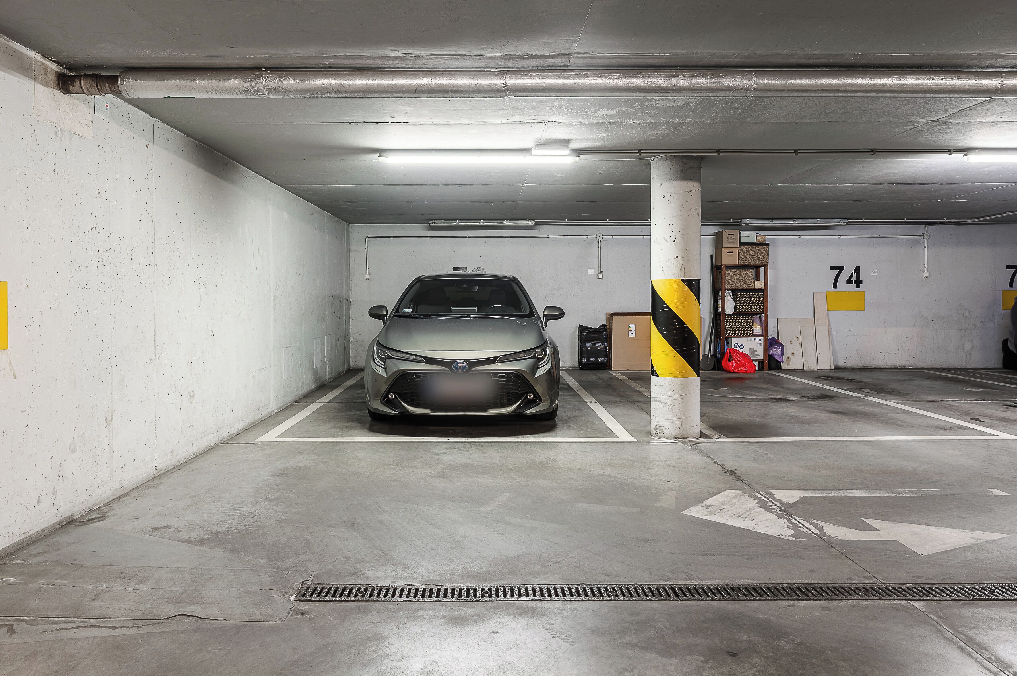 A parking garage with a car parked in a spot marked with the number 74.