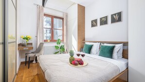 A neatly arranged bedroom with a bed, a desk, and a window.