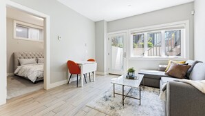 A modern living room with a sofa, a coffee table, and a dining area with a table and chairs. - Cozy & Convenient · 2 Mins from SkyTrain · Central Location (Vancouver)