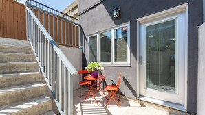 A staircase leading to a balcony with a table and chairs, a potted plant, and a window with blinds. - Cozy & Convenient · 2 Mins from SkyTrain · Central Location (Vancouver)