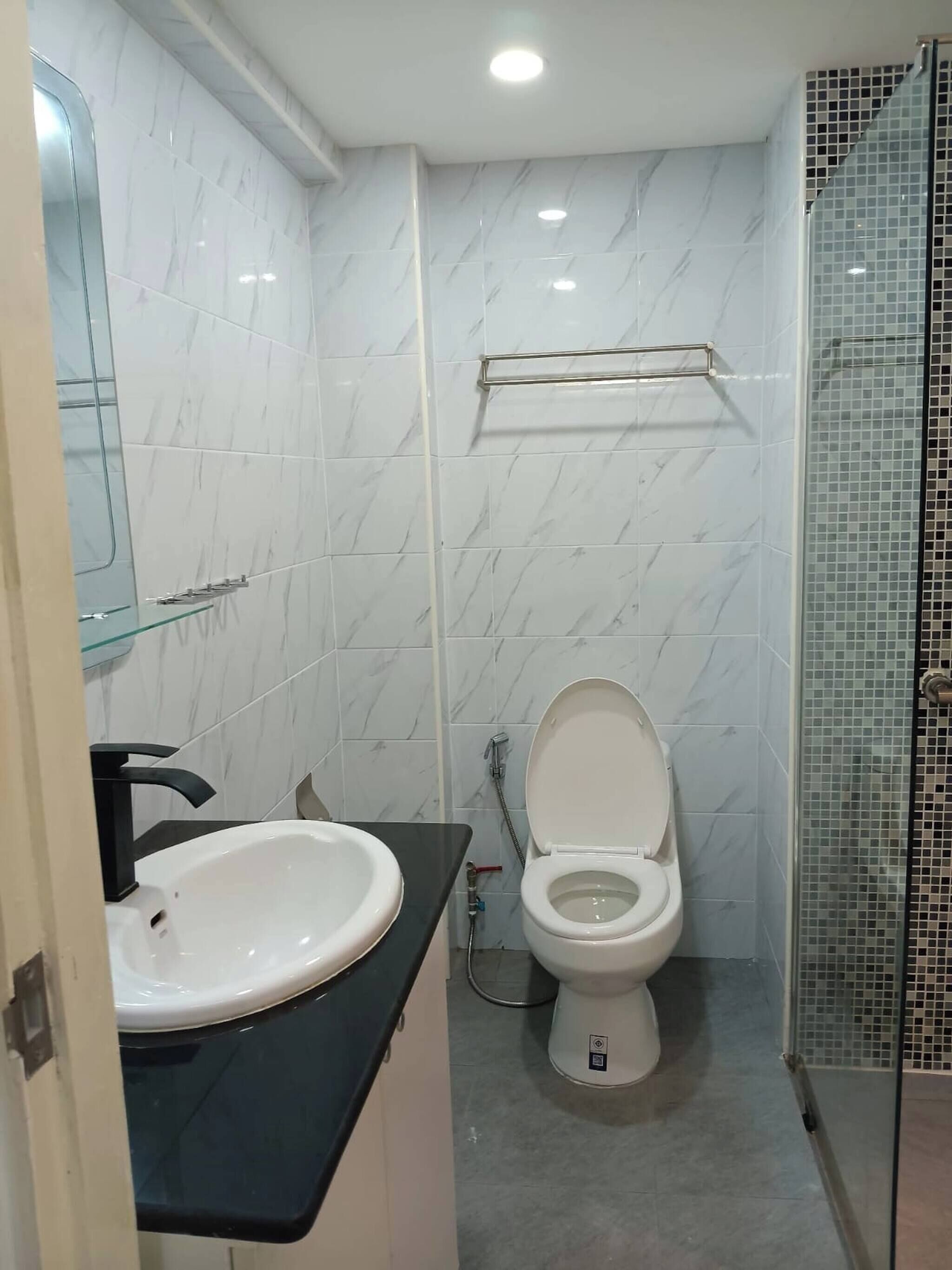 Baño con inodoro blanco, lavamanos y cabina de ducha de vidrio.