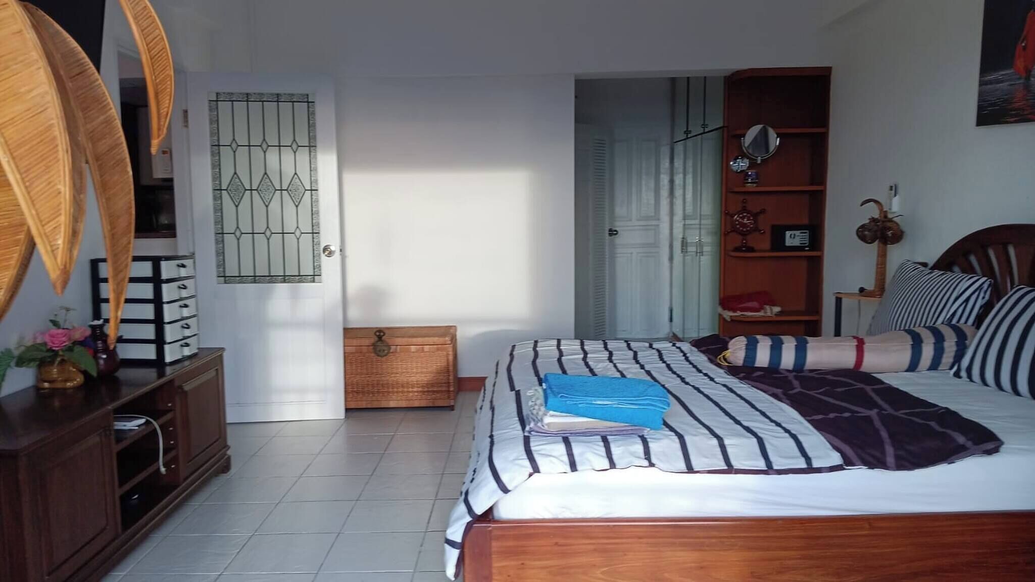 A bedroom with a bed, wooden headboard, bedside table, and a wardrobe.
