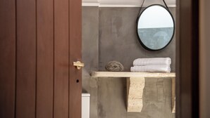 Une salle de bain avec une porte en bois, un miroir rond, un porte-serviettes et un distributeur de serviettes.