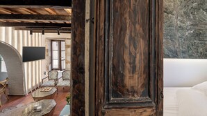 Un intérieur rustique avec un plafond en bois, un grand téléviseur fixé au mur et un coin salon confortable avec un canapé et des fauteuils.