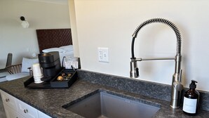 A modern kitchen with a granite countertop, a stainless steel sink, a coffee maker, and a bottle of dish soap. - Juniper Motel-King Suite-Room 22*Cook Top*Waterfront*Lake Access*Dock (Greenville)