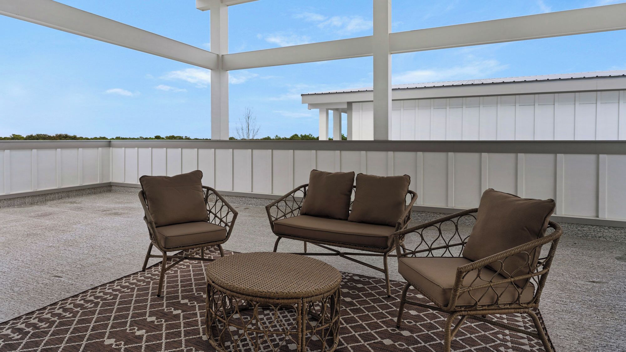 A covered outdoor seating area with wicker furniture and a patterned rug.