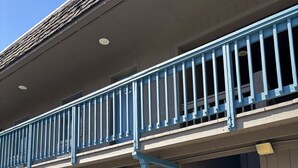 Un motel avec un balcon bleu, une porte bleue portant le numéro 21 et un escalier menant à l’entrée.