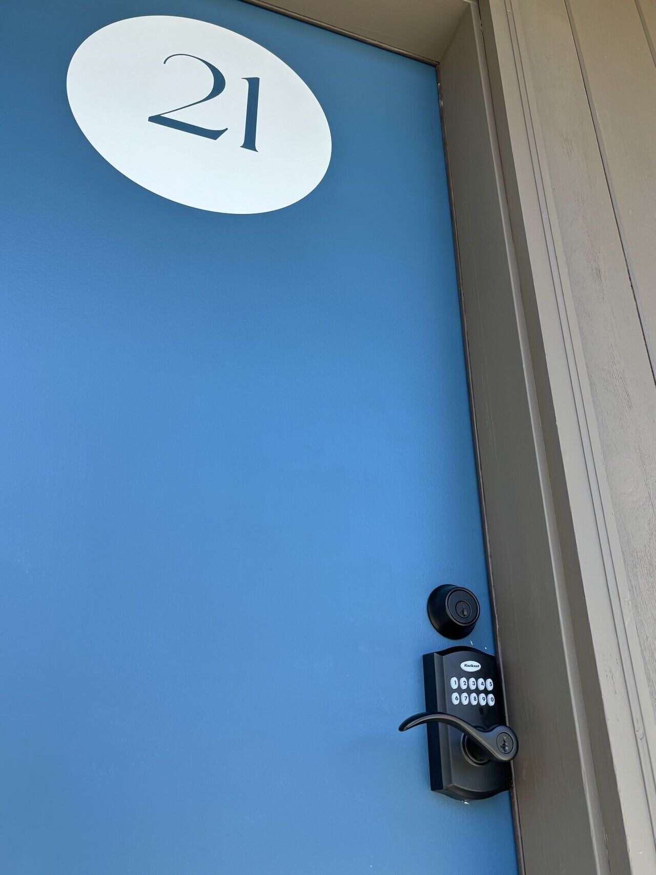 A blue door with a white number '21' and a doorbell with a keypad.