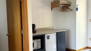 Cozinha compacta com geladeira, micro-ondas e um varal.