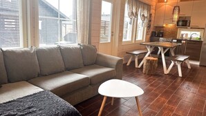 Ein gemütliches Wohnzimmer mit einer Couch, einem kleinen runden Tisch und einem Essbereich mit Holztisch und Stühlen.