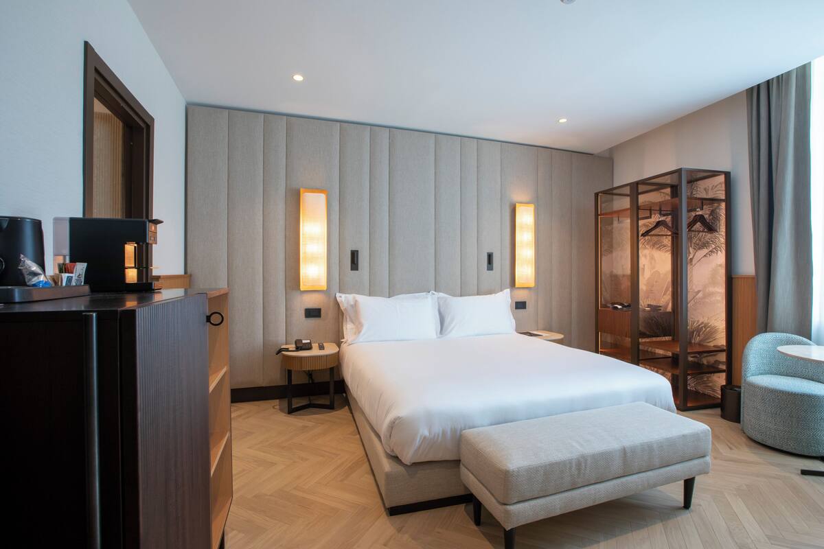 Ein modernes Hotelzimmer mit einem großen Bett, Nachttischen, einem Kleiderschrank und einer Sitzecke.
