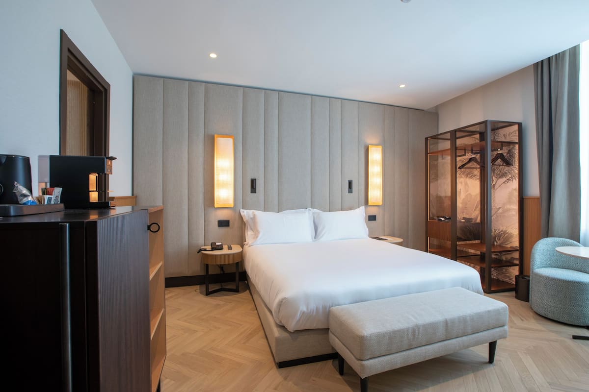Ein modernes Hotelzimmer mit einem großen Bett, Nachttischen, einem Kleiderschrank und einer Sitzecke.