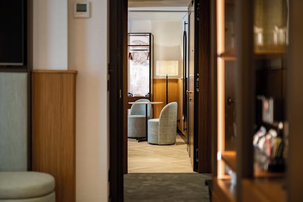 Un couloir menant à un espace détente avec des fauteuils et une lampe.