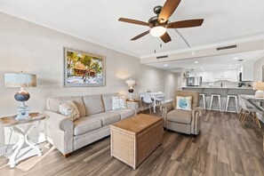 A modern living room with a sofa, armchairs, a coffee table, and a ceiling fan.