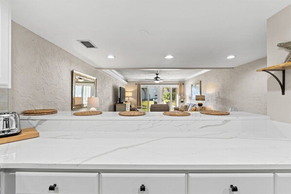A spacious kitchen with a marble countertop, built-in cabinets, and a central island.