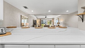 A modern kitchen with a large marble countertop, built-in cabinets, and a ceiling fan. - 1BR Ground Floor, Pets, Beach & Pool, Sleeps 4 (Panama City Beach)