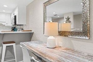 A kitchen with white cabinets, a wooden countertop, a bar stool, and a decorative lamp.