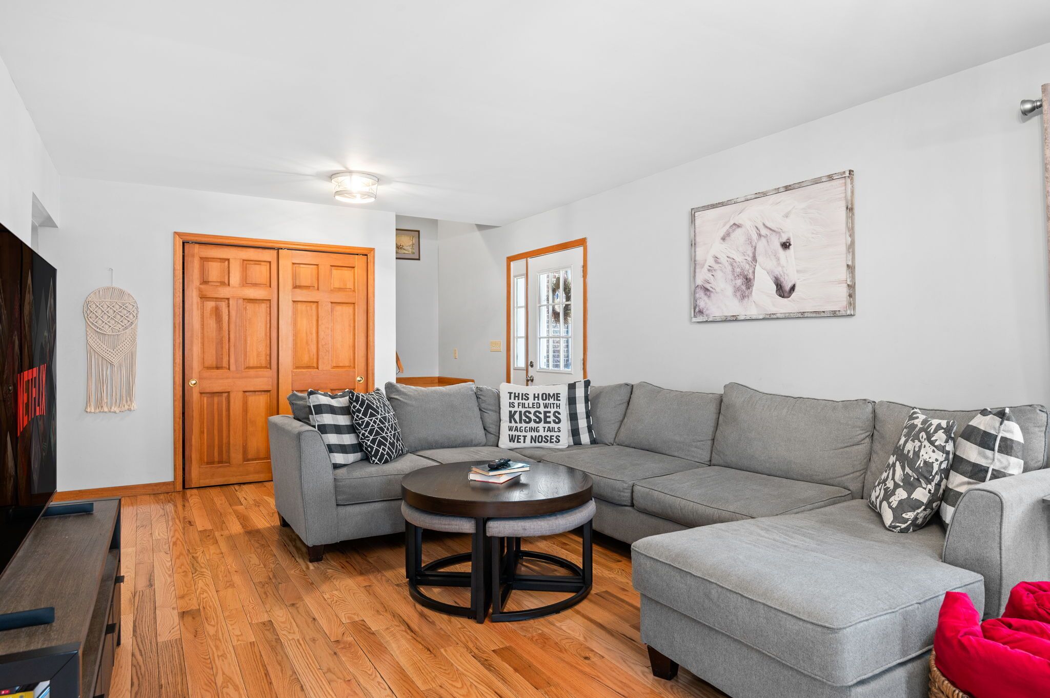A modern living room with a grey sectional sofa, a round coffee table, and a wooden floor.