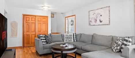 A modern living room with a grey sectional sofa, a round coffee table, and a wooden floor.