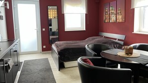 Ein gemütliches Schlafzimmer mit Bett, Schreibtisch, Stuhl und Esstisch.