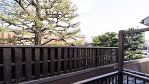 A wooden fence with a metal railing, a tree, and buildings in the background. - Gion Dinosaur (Kyoto)