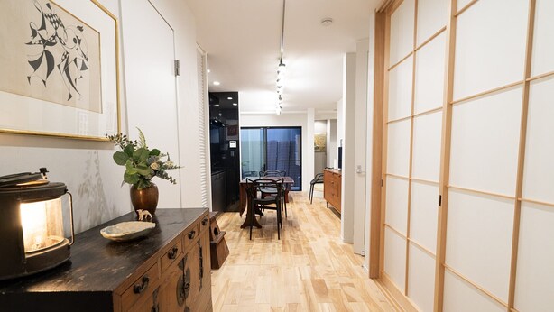 A hallway with a wooden floor, a dining area with a table and chairs, a kitchen area, and a sliding door. - Gion Dinosaur (Kyoto)
