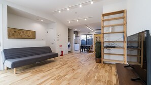 A modern interior with a sofa, wooden flooring, a TV, and a bookshelf. - Gion Dinosaur (Kyoto)