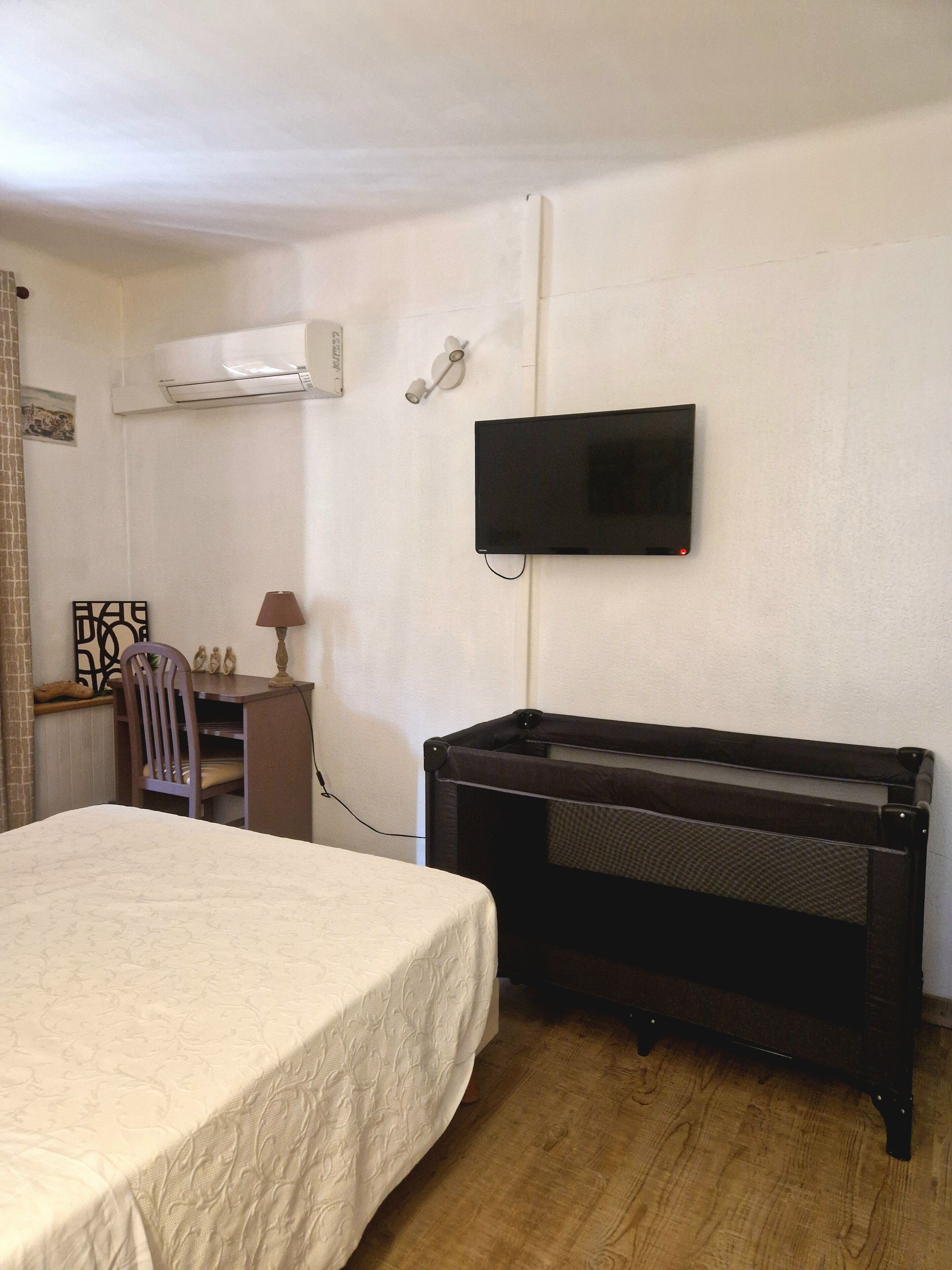 A hotel room with a bed, a desk, a chair, a television, and a piano.