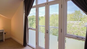 Ein Zimmer mit großen Fenstern, einer weißen Tür und einem kleinen Tisch in Weiß.