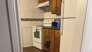 A kitchen with wooden flooring, white cabinets, and a stove. - The perfect spot/beachfront cozy cottage (Wasaga Beach)