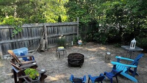 A backyard with a wooden fence, outdoor furniture including chairs and a table, a bird feeder, and a small garden area. - The perfect spot/beachfront cozy cottage (Wasaga Beach)