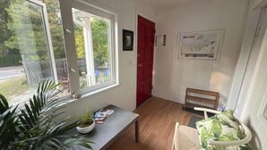 A room with a wooden floor, a desk with a plant, a chair with a leaf-patterned cushion, a red door, and a wall-mounted map. - The perfect spot/beachfront cozy cottage (Wasaga Beach)