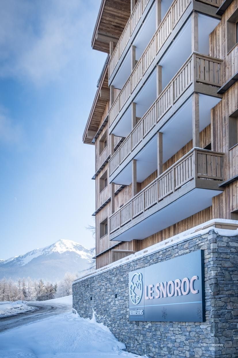 A multi-story hotel with wooden balconies and a stone facade.