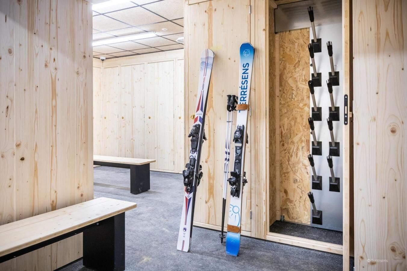 A wooden room with benches and skis leaning against the wall.