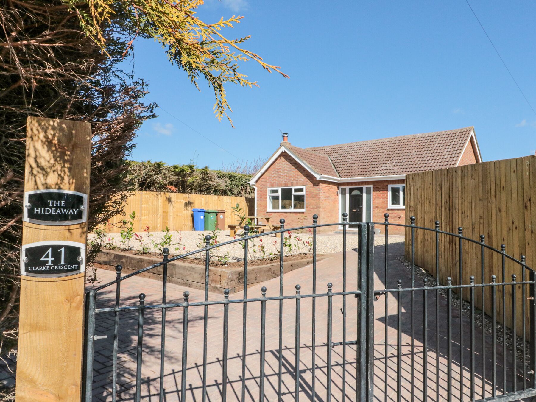 A residential property named "The Hideaway" at 41 Clarke Crescent, featuring a brick house with a tiled roof, a wooden fence, and a metal gate.