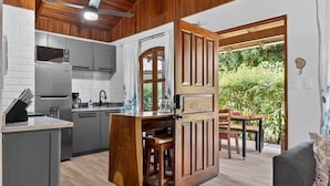 A compact kitchen with modern appliances, a wooden island, and a dining area with a view of greenery. - Tropical Perfection, Includes Kayak, Snorkel, Beach Gear, Walk To The Beach (Playa Potrero)
