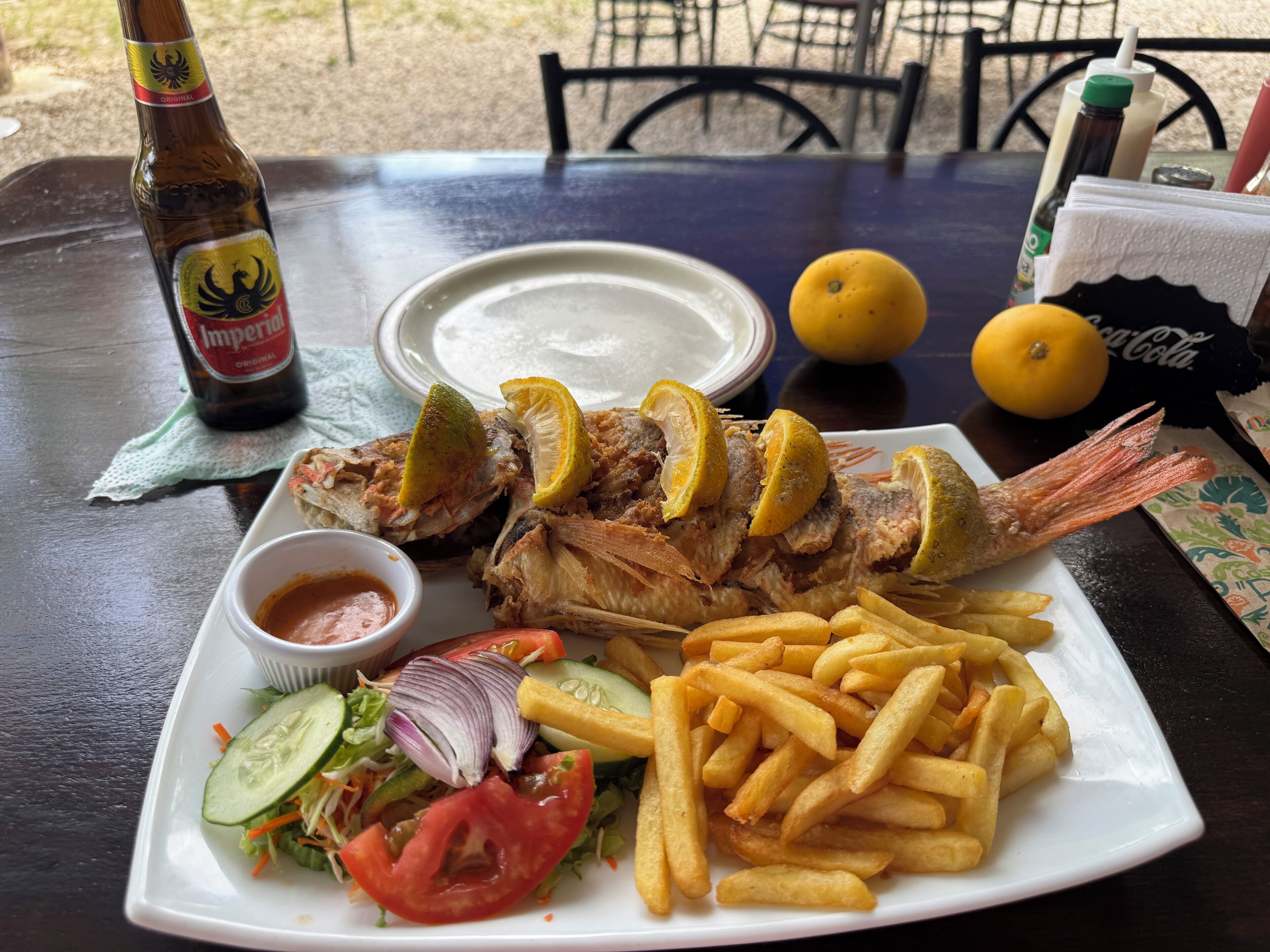A meal with fish, fries, salad, and a drink on a table.
