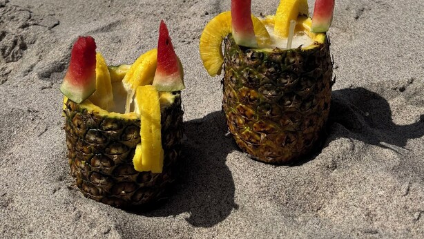 Two drinks on a sandy beach with ocean and rocky cliffs in the background. - Tropical Perfection, Includes Kayak, Snorkel, Beach Gear, Walk To The Beach (Playa Potrero)
