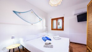 Una habitación de hotel con una cama, una mesita redonda con una lámpara, un televisor montado en la pared y una ventana con vistas al exterior.