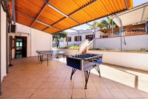 Relax in the outdoor patio area, featuring a foosball table, table tennis table, and covered seating area.