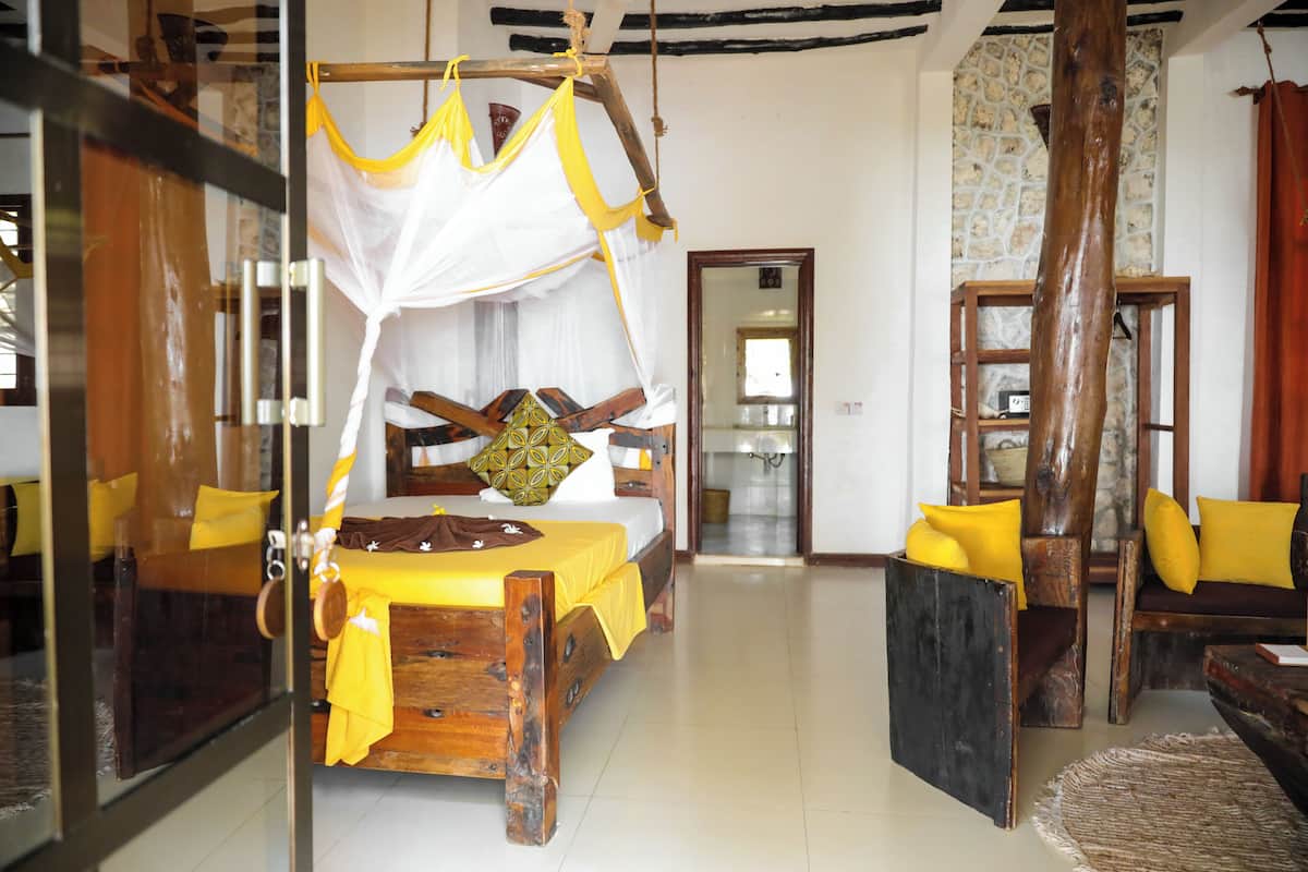 A room with a bed, wooden furniture, and a stone wall.