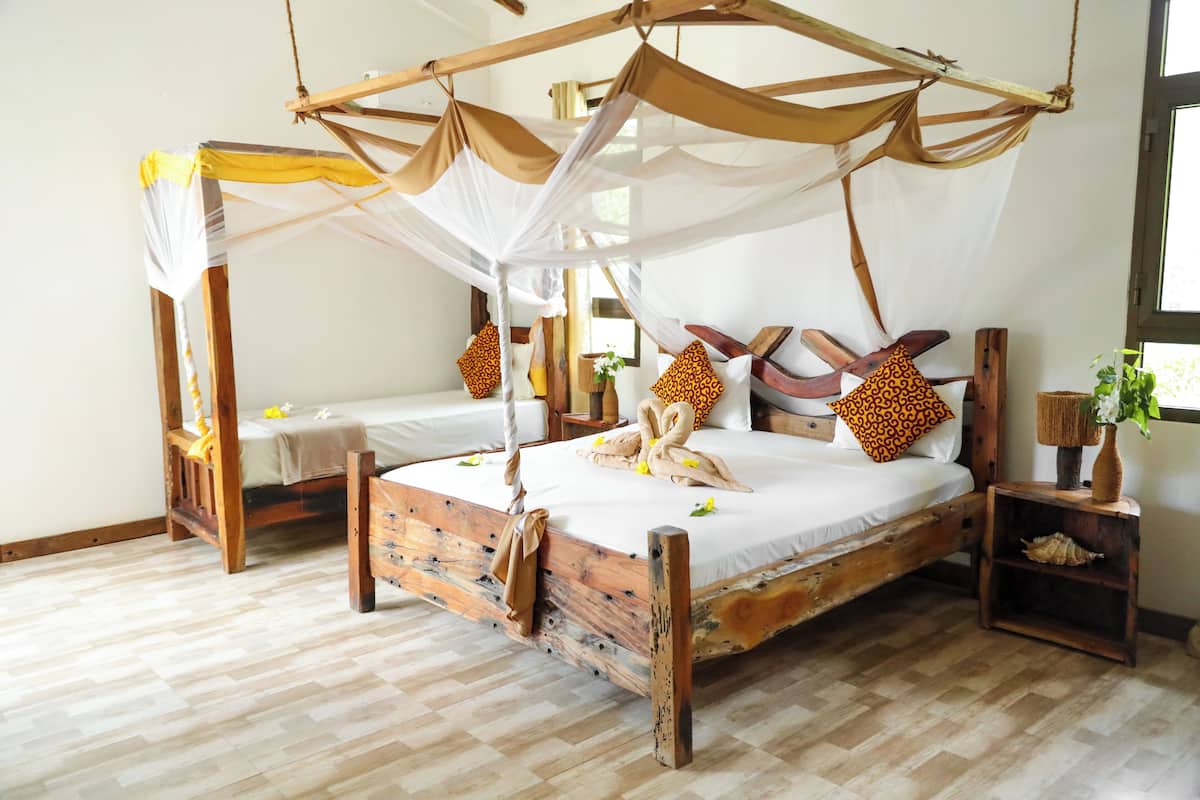 A wooden four-poster bed with a canopy, two bedside tables, and a nightstand with a vase.
