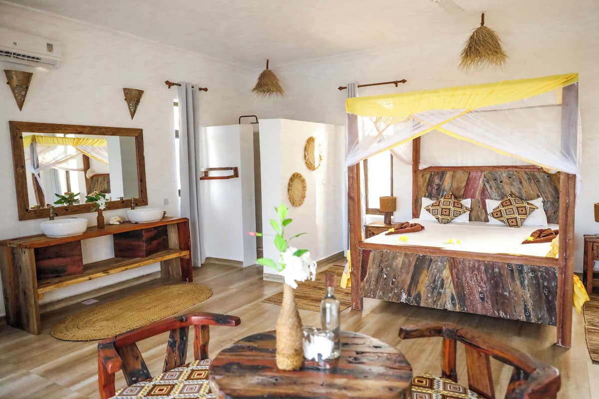 A bedroom with a wooden bed, a bedside table, a mirror, and a window with curtains.