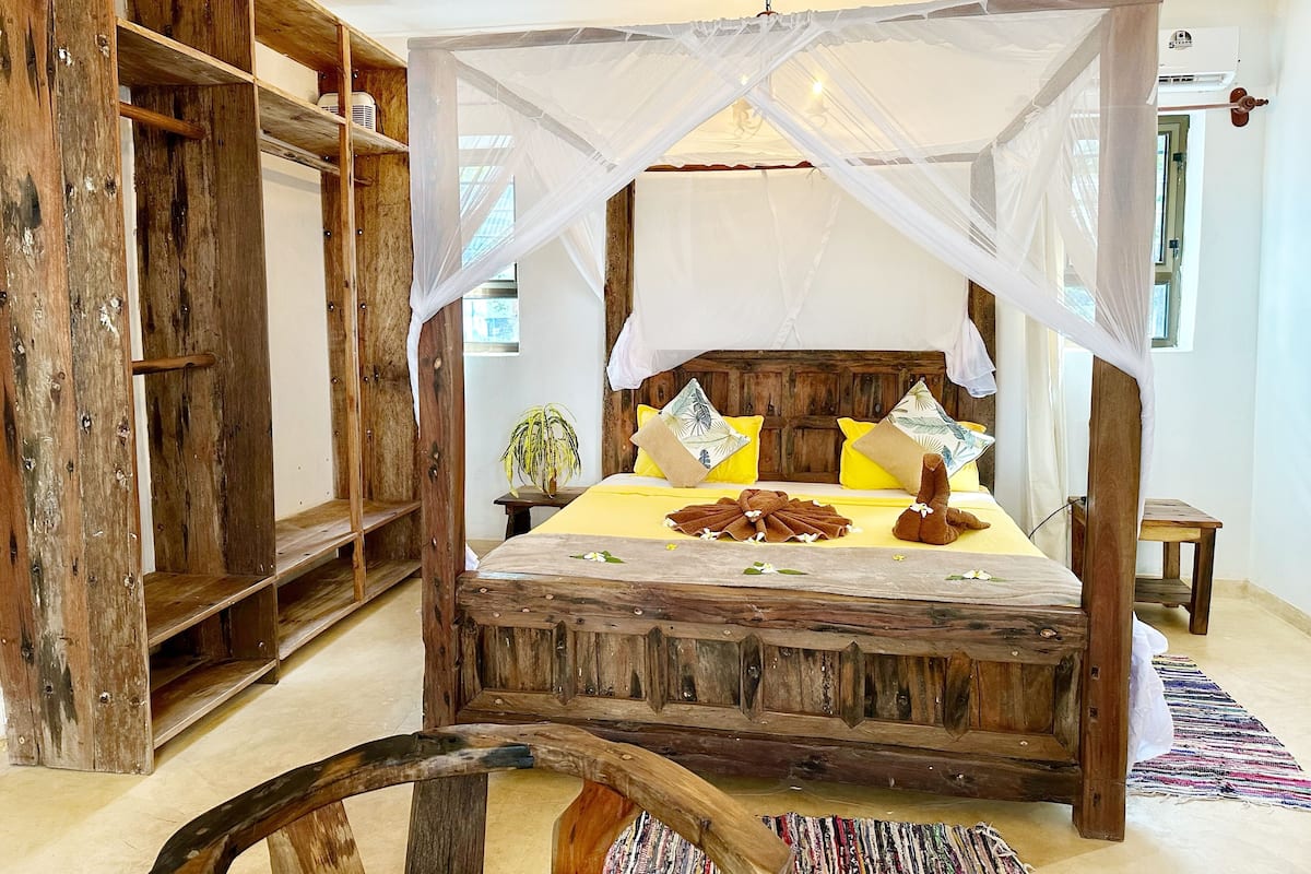 A rustic wooden bed with a canopy, yellow bedding, and decorative pillows.
