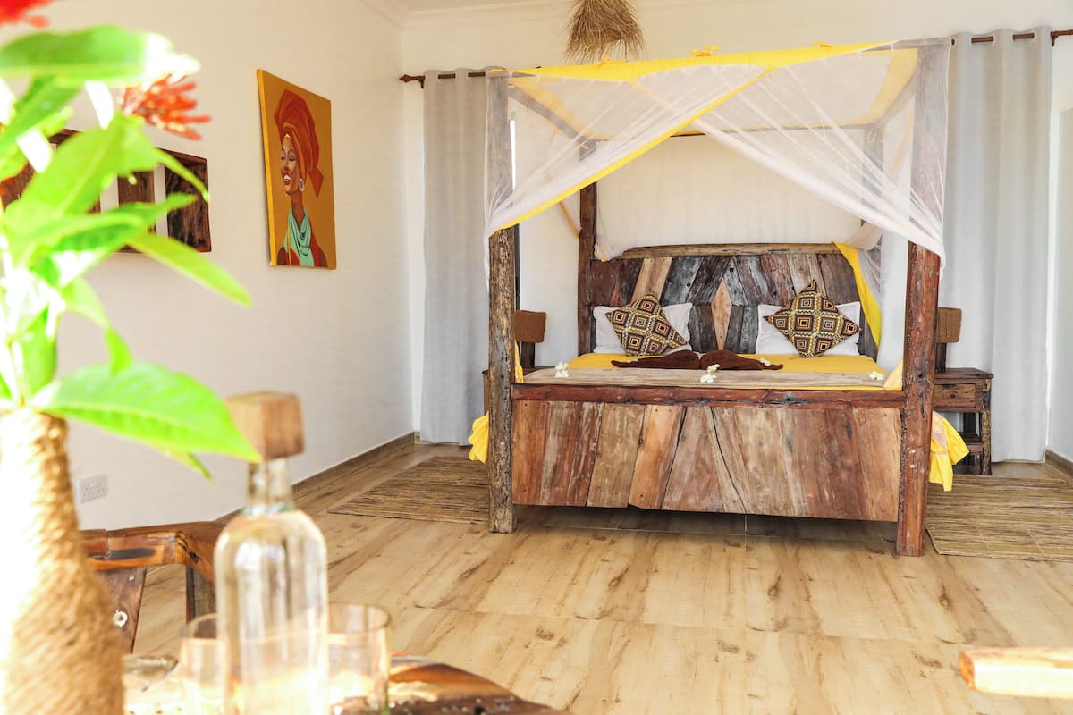 A rustic wooden bed with a canopy, a small bedside table, and a wall-mounted shelf.