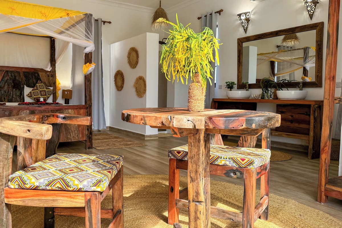 A rustic wooden dining area with benches and a central table, surrounded by decorative wall art and a hanging plant.